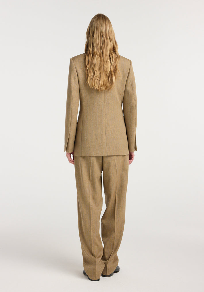Back view of a person wearing a tailored tan suit with subtle heritage stripes, featuring the Overlap lapel blazer | heritage stripe paired with matching trousers.