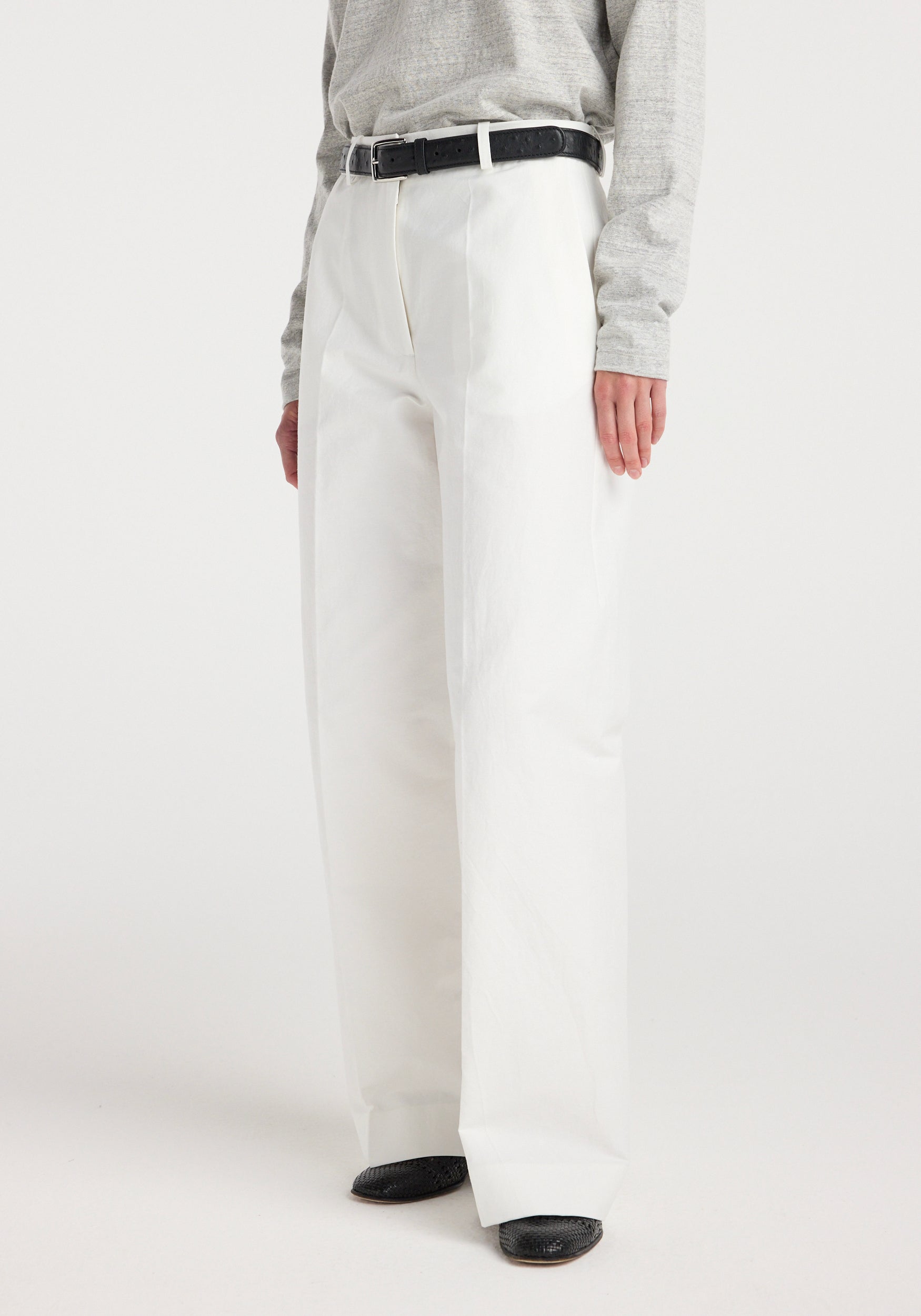 Front view of a person wearing Classic loose fit chino | optic white paired with a light grey long-sleeve top, black belt, and black shoes.