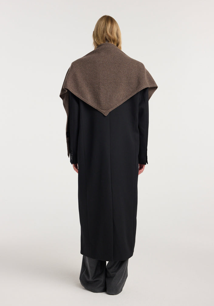 Woman wearing a black long coat over a gray turtleneck and trousers, with a Large knitted triangle scarf | brown melange draped over her shoulders.