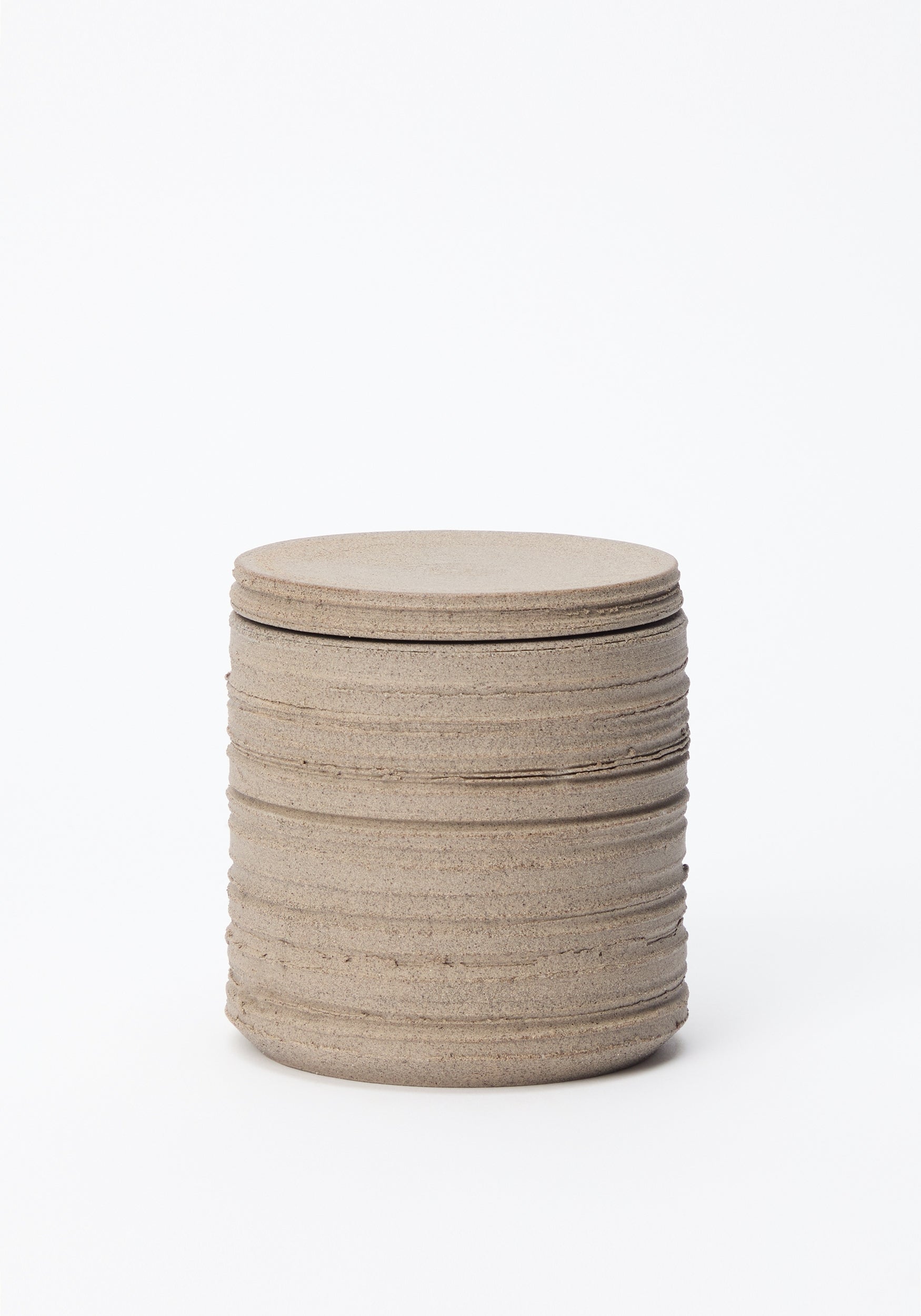 Diplomatico Scented Candle | stone in a textured, cylindrical stone-colored container with horizontal grooves, showcased against a white background.