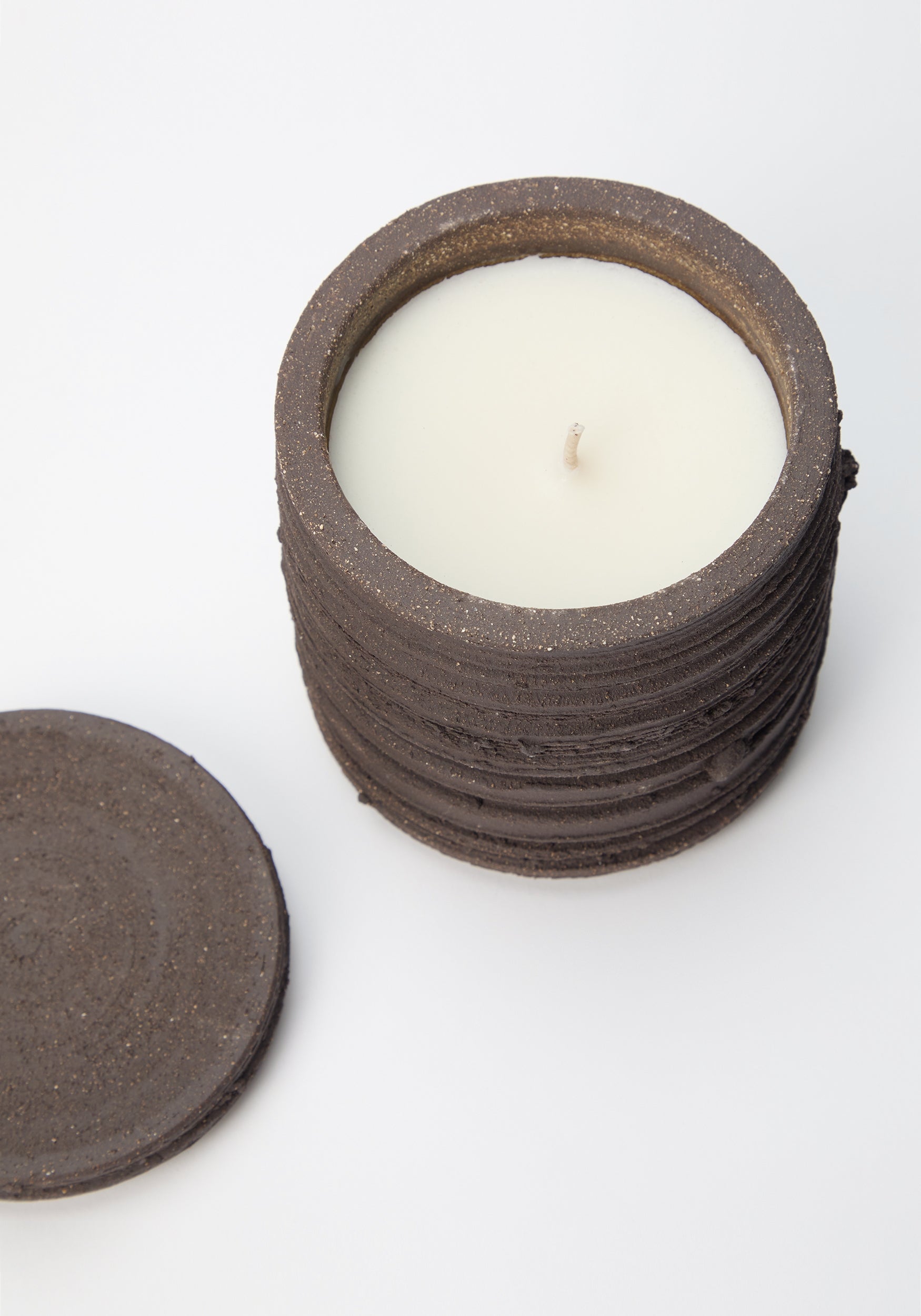 Diplomatico Scented Candle | soil in a textured dark brown ceramic container with a matching lid placed beside it, featuring a clean white wax surface and a single wick.