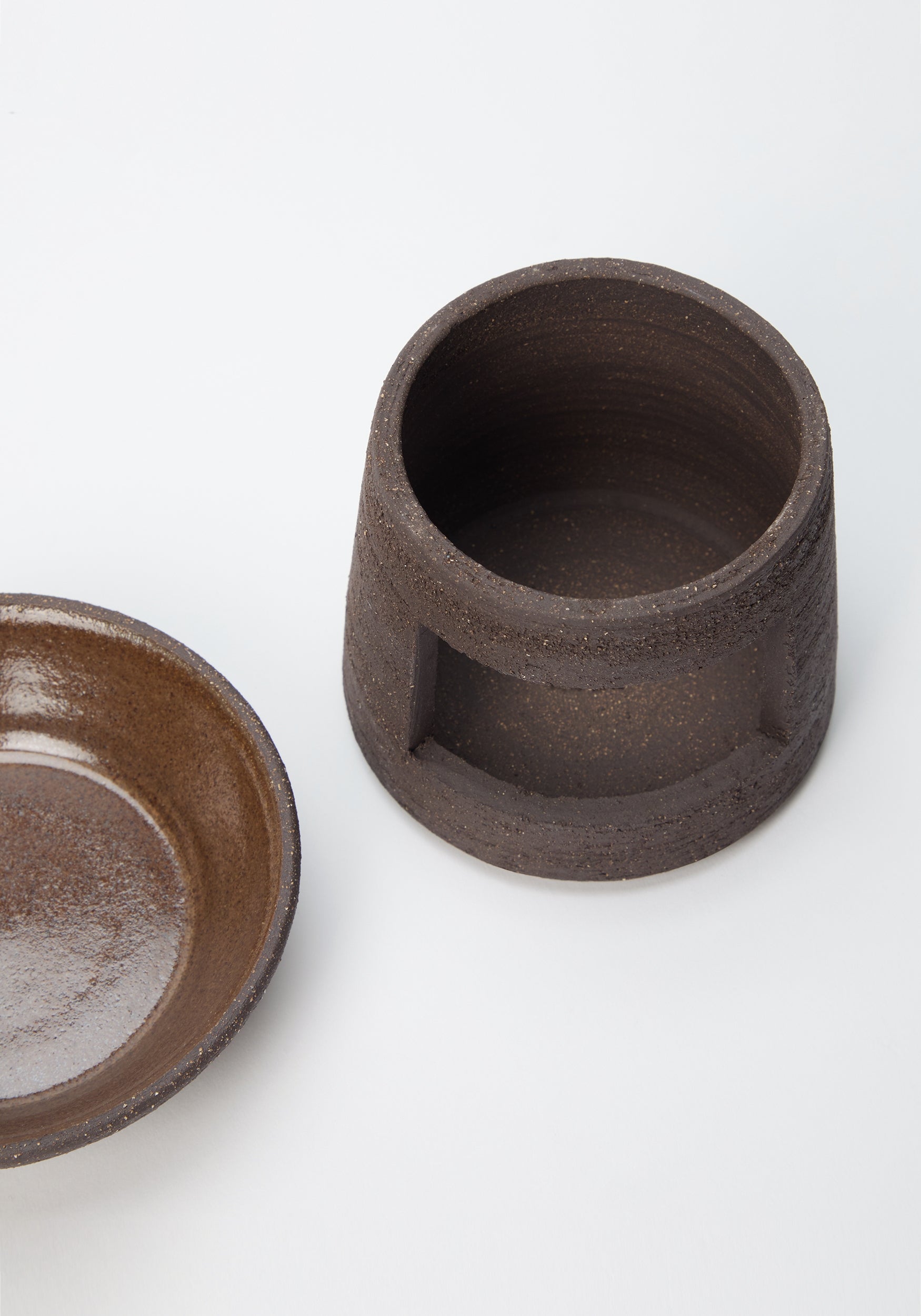 Ceramic Oil Burner | soil showing a dark brown textured ceramic base with an opening for a tealight and a separate shallow bowl for holding essential oils or wax melts on a white background.