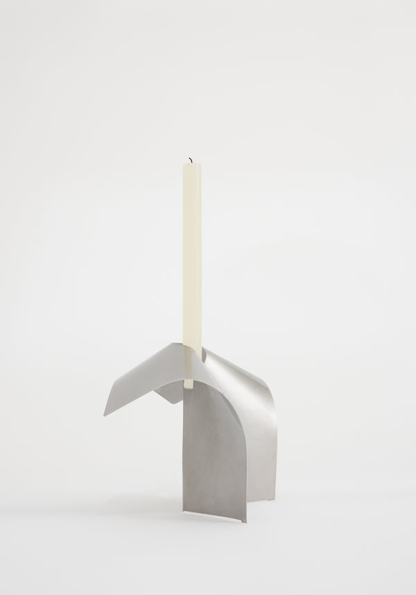 Stainless steel candle holder featuring a minimalist, tripod-like design with interlocking curved panels, showcasing a tall taper candle in an elegant, modern style.