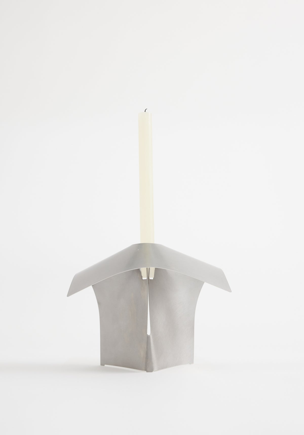 Stainless steel candle holder designed by Paul Coenen, featuring an origami-style bent metal frame holding an unlit taper candle, handcrafted in the Netherlands.