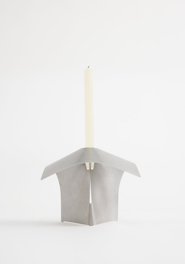 Stainless steel candle holder designed by Paul Coenen, featuring an origami-style bent metal frame holding an unlit taper candle, handcrafted in the Netherlands.