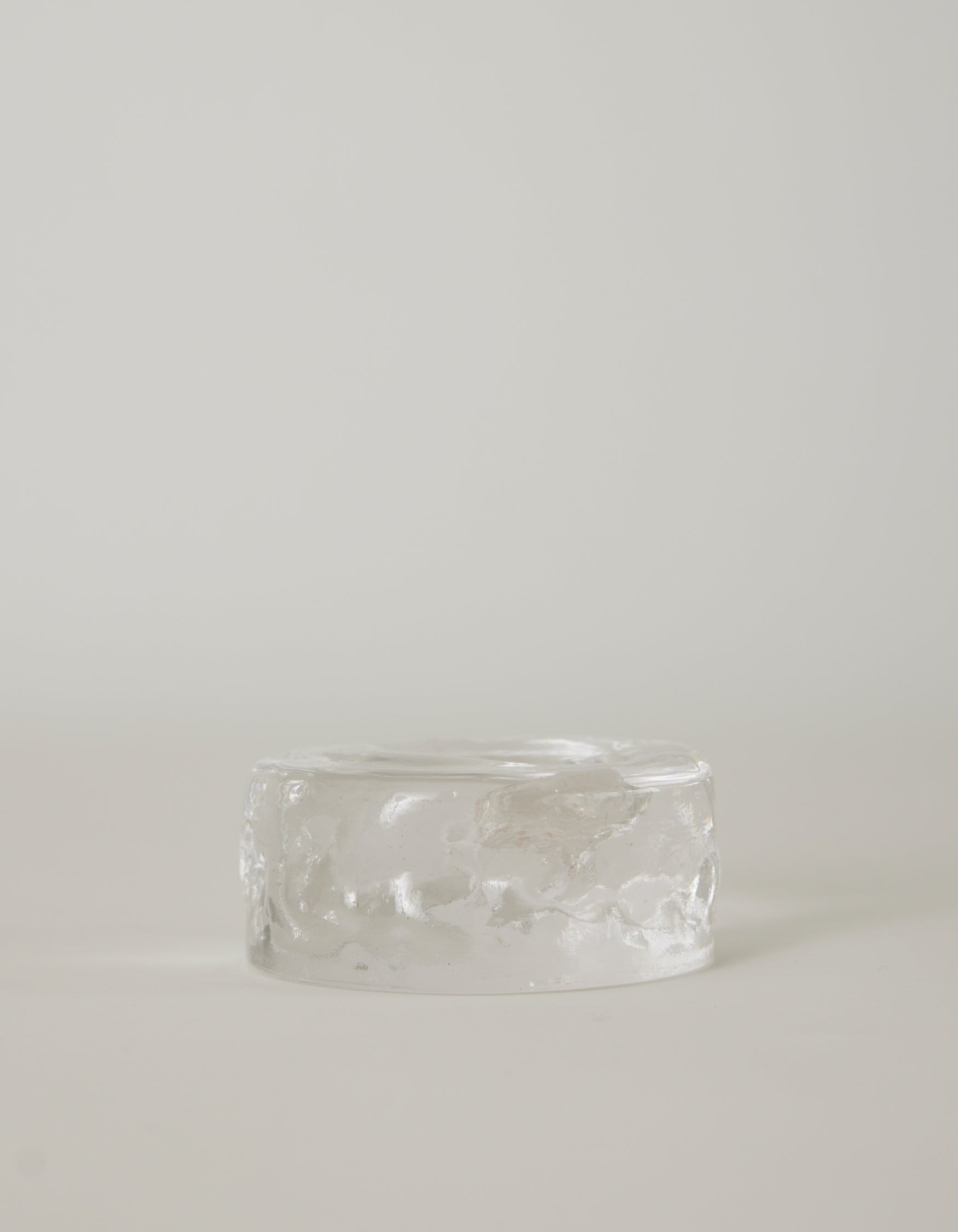 Presse-papier & holder by Szkło Studio: A clear, rippled, glass-like cylinder, showcasing handcrafted, unique design with a raw, crystalline appearance.