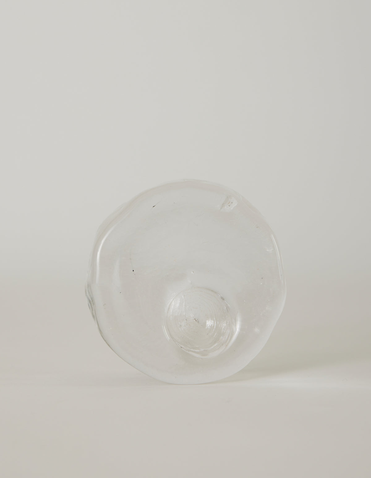 Presse-papier & holder | Glass: Hand-blown clear glass with an irregular circular shape and central dome, featuring ripples and imperfections, highlighting unique craftsmanship.