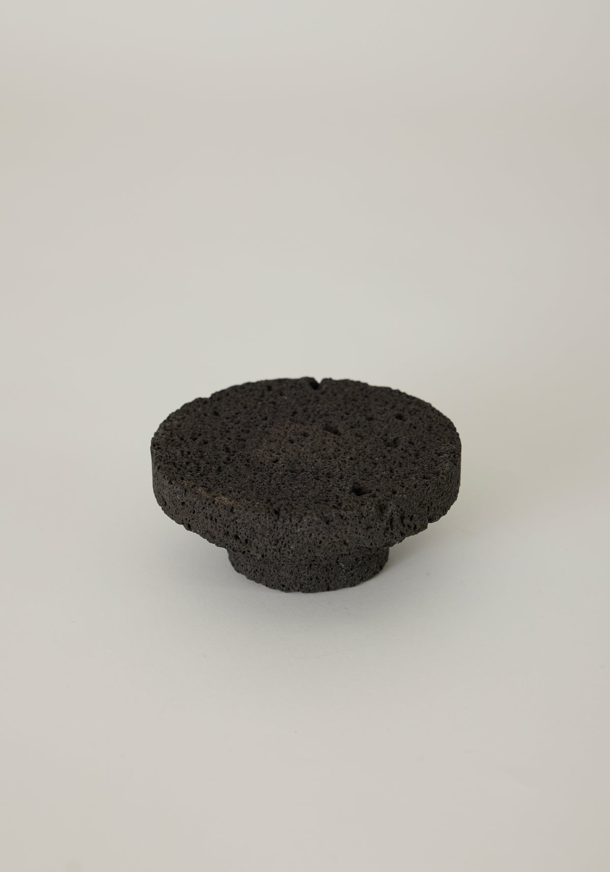 Elevated Sculptural Tray crafted from lava stone, featuring a porous texture with a circular design and smaller base, handcrafted by Louis Crombag in the Netherlands.