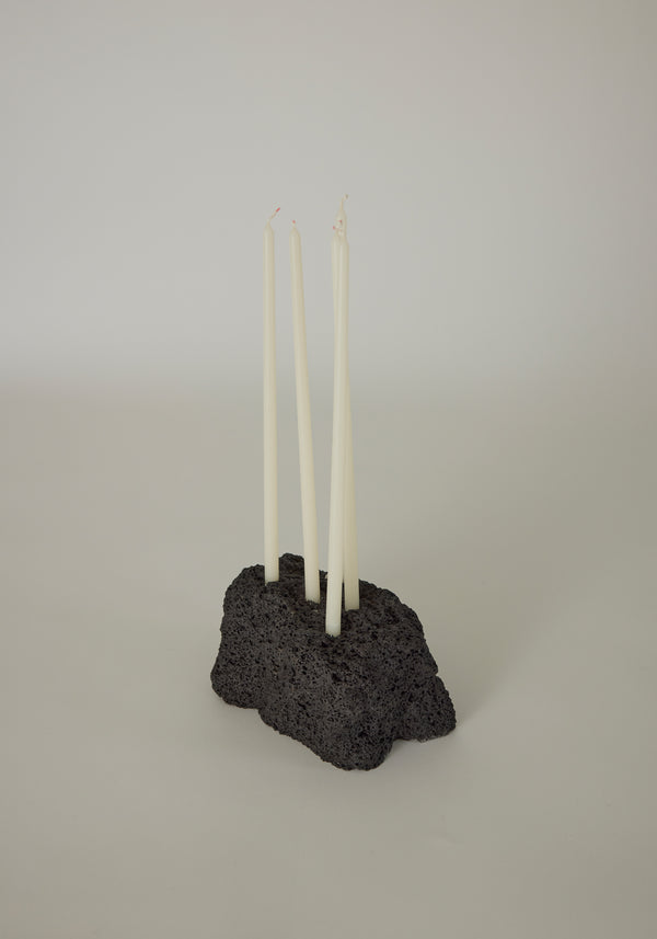 Sculptural Stone Candle Holder featuring four white taper candles in a handcrafted, porous black lava stone base by Dutch artist Louis Crombag.