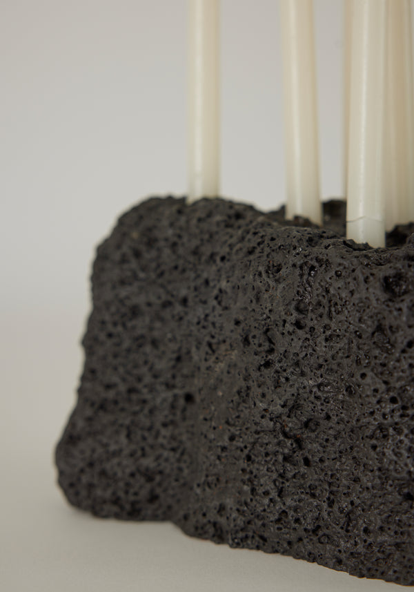 Sculptural Stone Candle Holder made from porous black lava stone, featuring six slender white taper candles, handcrafted by Dutch artist Louis Crombag.