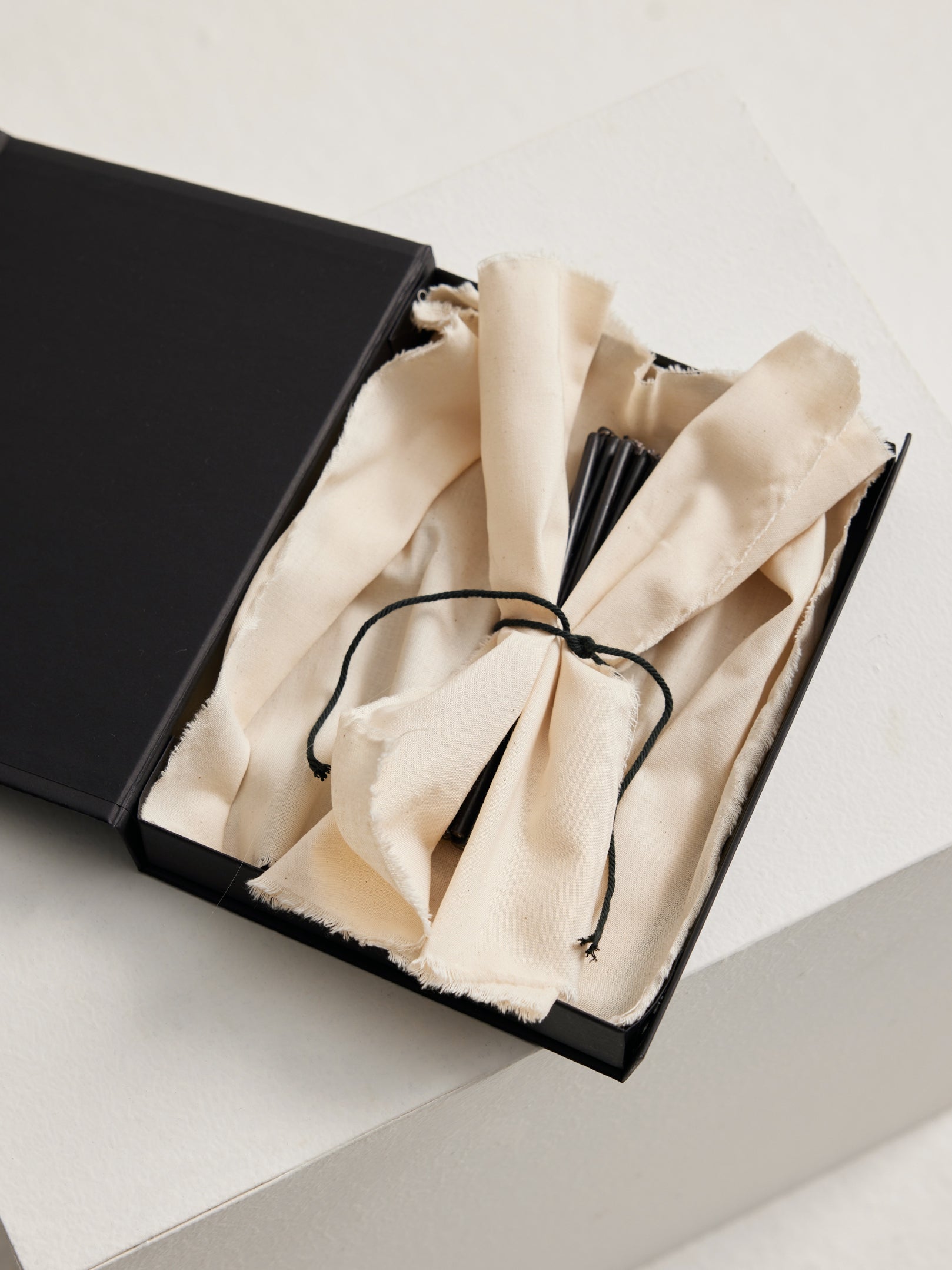 Candles 5mm | noir in a matte-black box with unbleached cotton cloth and incense-like sticks, highlighting minimalist design and presentation.