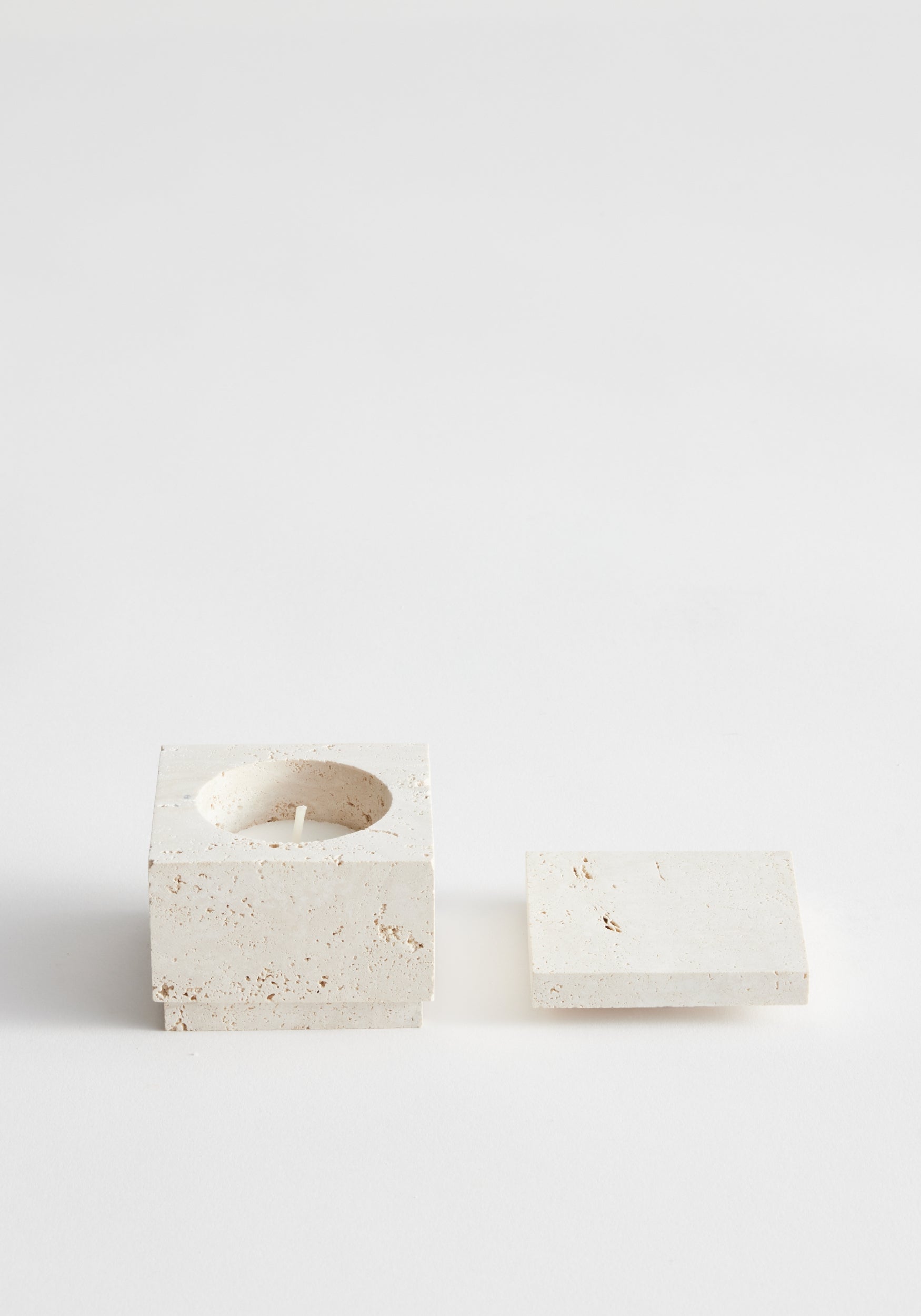 Tealight box | travertine: Two small square travertine pieces, one with a tealight recess and lid beside it, handcrafted by Louis Crombag in the Netherlands.