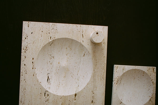 Large tray | travertine: Rectangular stone slab with circular recess, includes decorative cylinder for candles. Handcrafted in the Netherlands from Italian travertine.