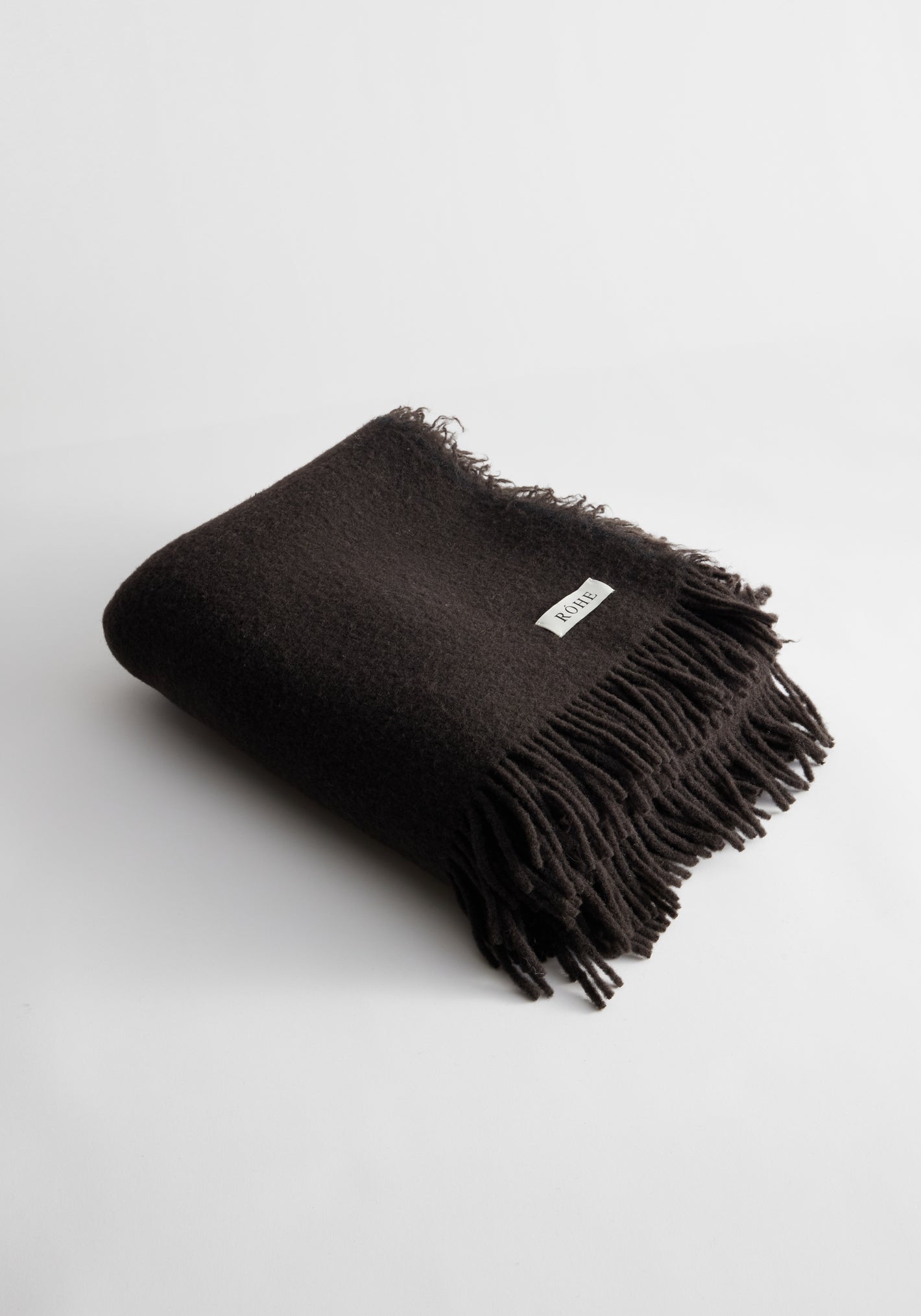 Chocolate Wool blanket with chunky fringes, woven label visible, crafted from Italian Lineaesse yarn, measures 130cm x 180cm, on a plain white background.