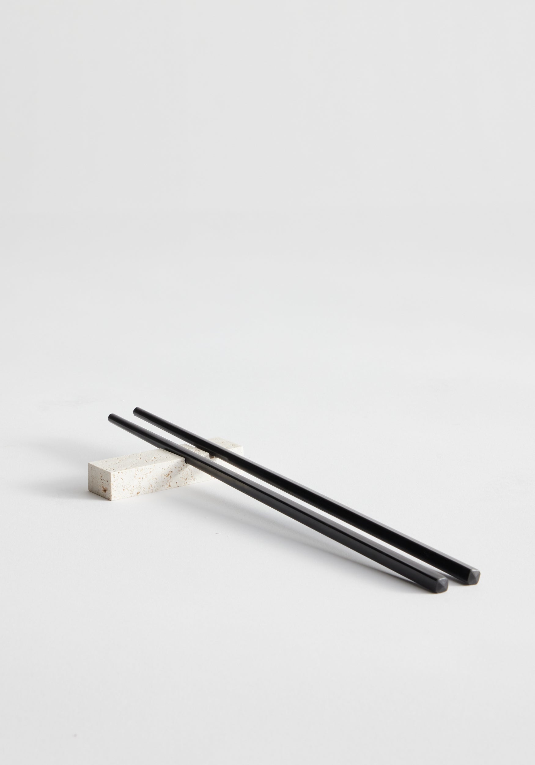 Black chopsticks resting on a rectangular travertine chopstick holder | Chopstick holders | travertine.