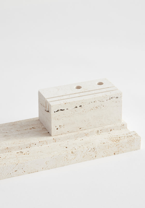 Desk organizer | travertine: A sculptural desk organizer with a flat slab base and a grooved, hole-bored block, handcrafted from unique leftover Italian travertine.