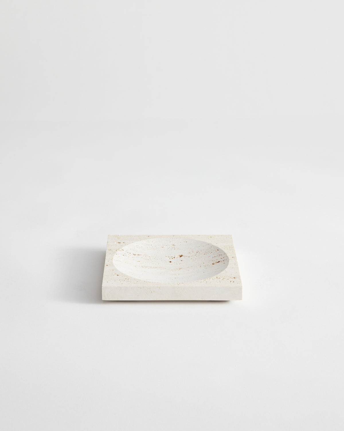 Small tray | travertine: A square stone tray with a central circular depression, handcrafted from speckled travertine, measuring 16cm by 16cm, designed by Louis Crombag.
