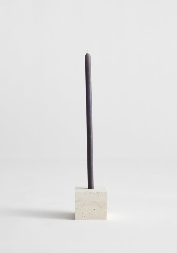 Two-way cube candleholder in travertine, showcasing a dark gray taper candle in a cube-shaped natural stone holder, handcrafted by Louis Crombag in the Netherlands.
