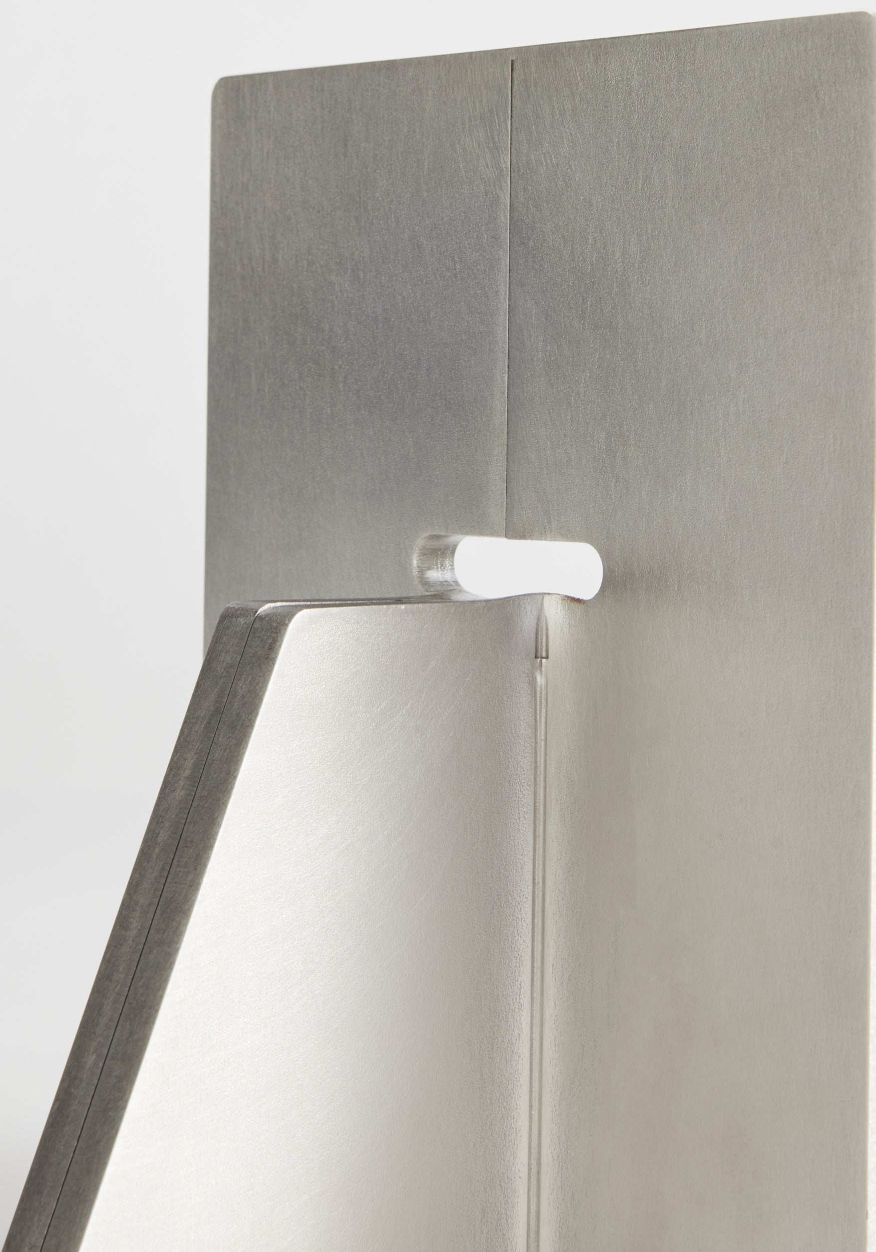 Close-up detail of a modern, minimalist stainless steel bookend showing the brushed metal texture and clean geometric design, Stainless steel bookends | stainless steel.