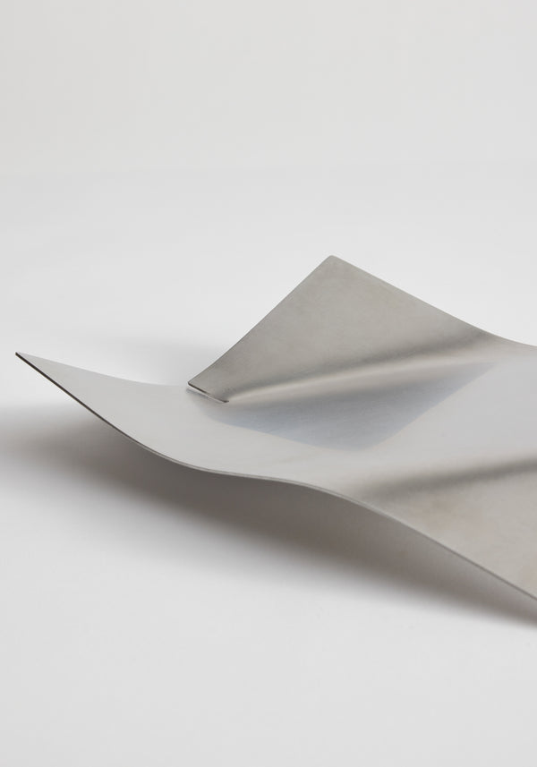 Stainless steel bowl with minimal bended shape, featuring two thin, curved sheets creating gentle wave-like highlights and shadows, handcrafted from stainless steel.