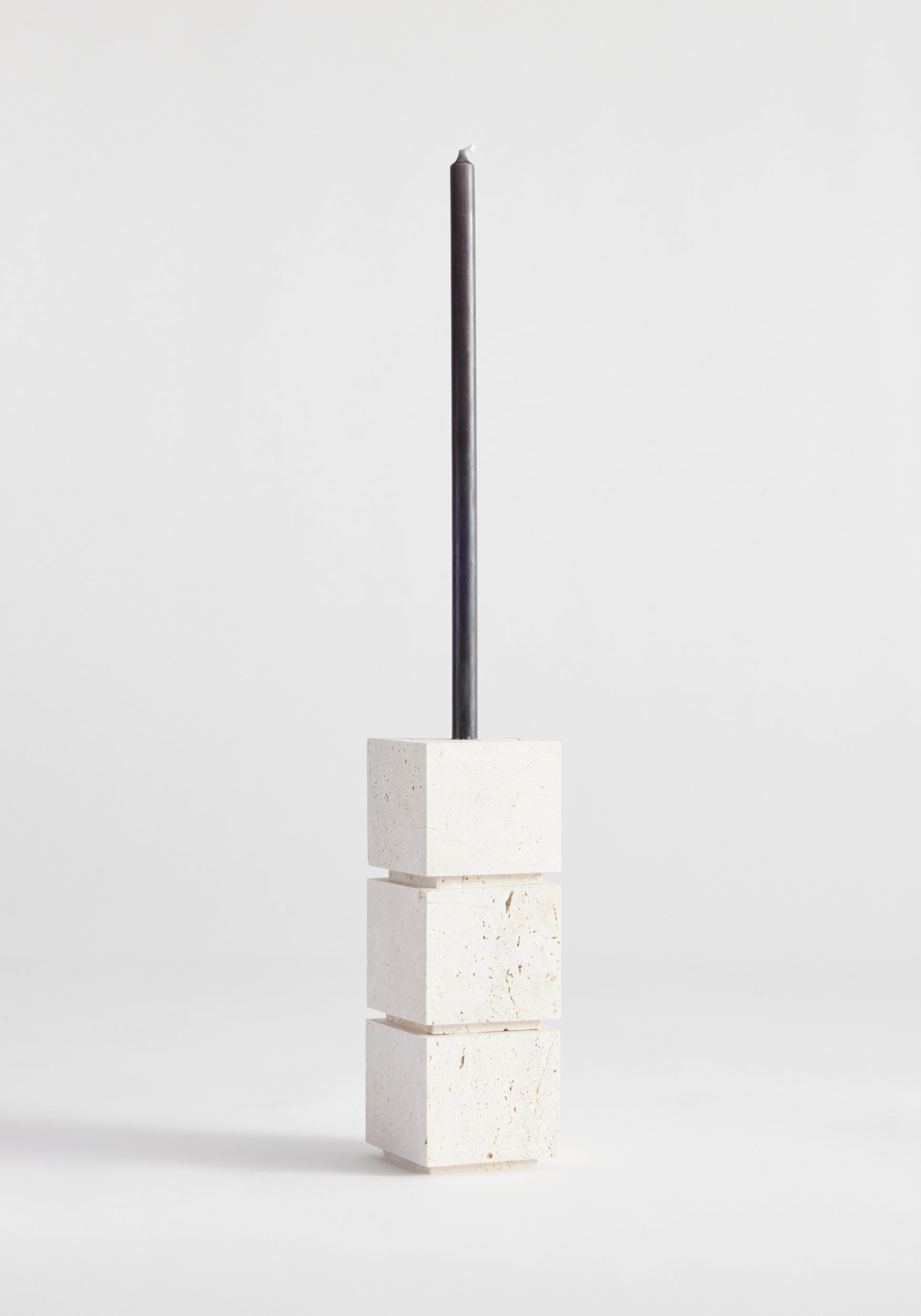 Sculptural candle holder small in travertine, featuring a black taper candle atop three white cubic stone blocks, handcrafted by Louis Crombag in the Netherlands.