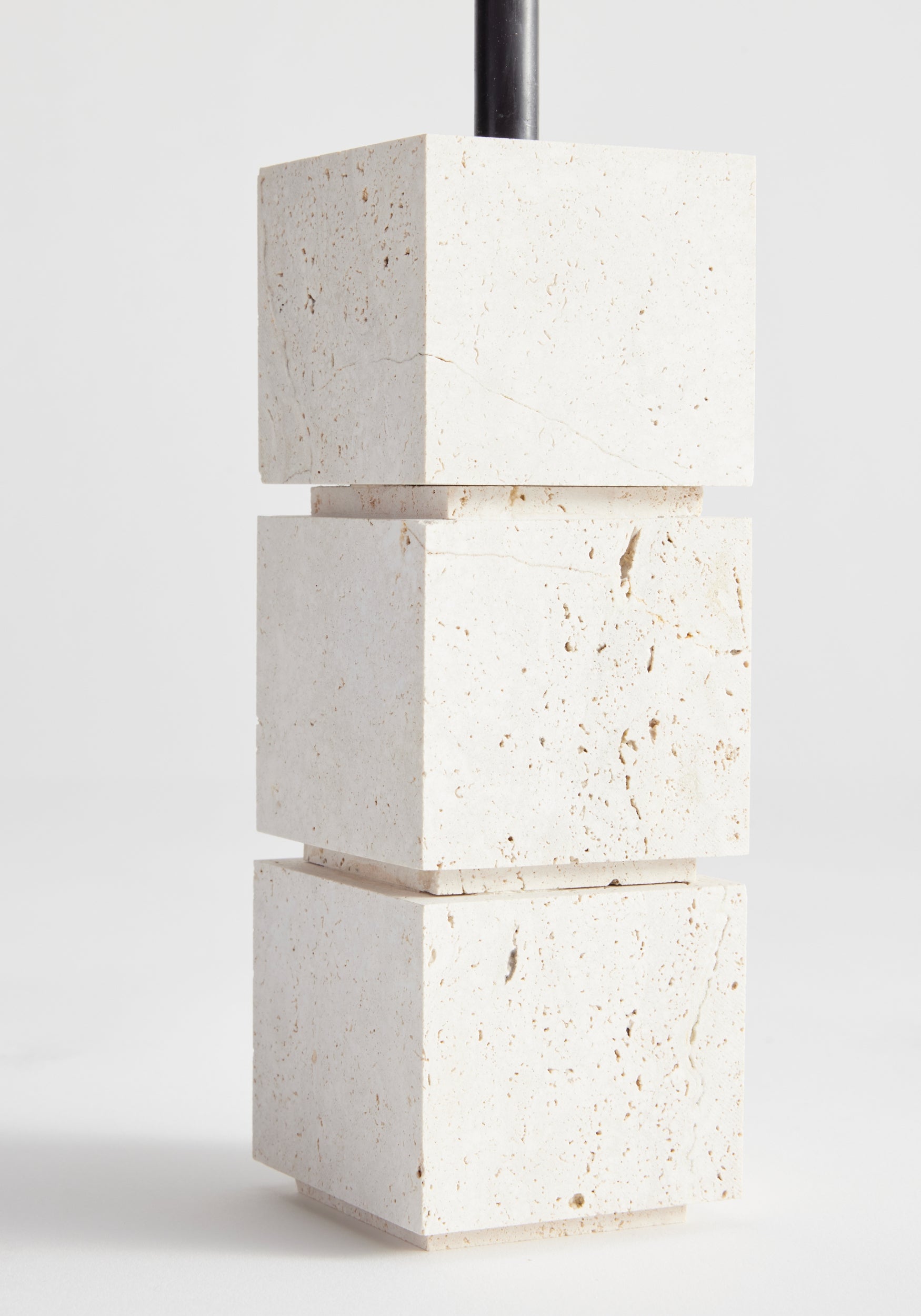 Sculptural candle holder small | travertine: Three stacked travertine cubes with a black metal rod for 10mm candles, handcrafted by Dutch artist Louis Crombag.