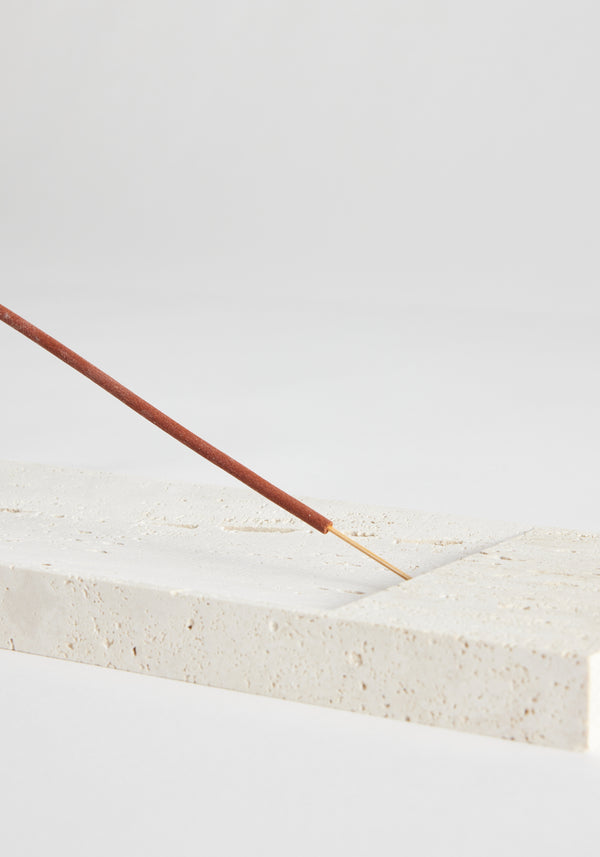 Incense holder tray in travertine, showcasing a slender incense stick on a handcrafted pale-beige block, designed by Louis Crombag in the Netherlands.