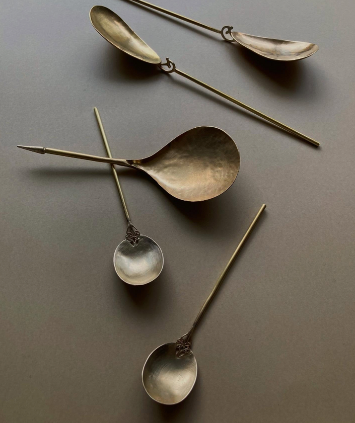 Tea Spoon: A brass-colored scoop with a textured handle, wire-wrapped to a slender rod, showcasing Misae Nikkei's handcrafted artistry from Kyoto.