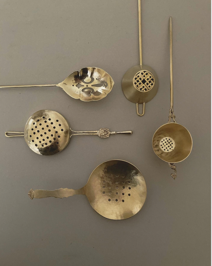 Tea Strainer: A collection of vintage-style, handcrafted brass strainers with intricate, lacy designs and decorative handles, inspired by traditional Japanese artistry.