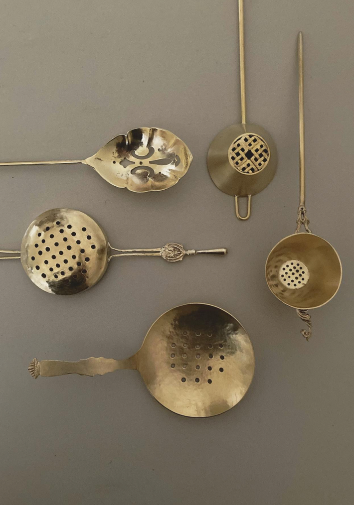 Tea Strainer: A collection of vintage-style, handcrafted brass strainers with intricate, lacy designs and decorative handles, inspired by traditional Japanese artistry.