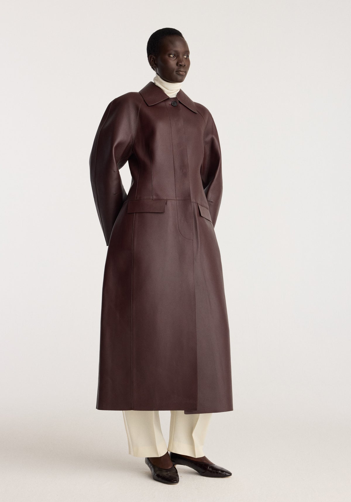 Sculptural Bonded Leather Coat | mahogany shown on a model with a structured collar welt pockets long silhouette and rich dark brown finish