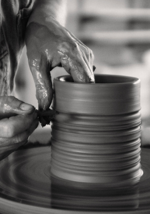 Hands sculpting clay vessel on wheel, showcasing craftsmanship of Diplomatico Scented Candle | stone, housed in handmade ceramic by Alex Gabriels, reflecting brutalist aesthetics.