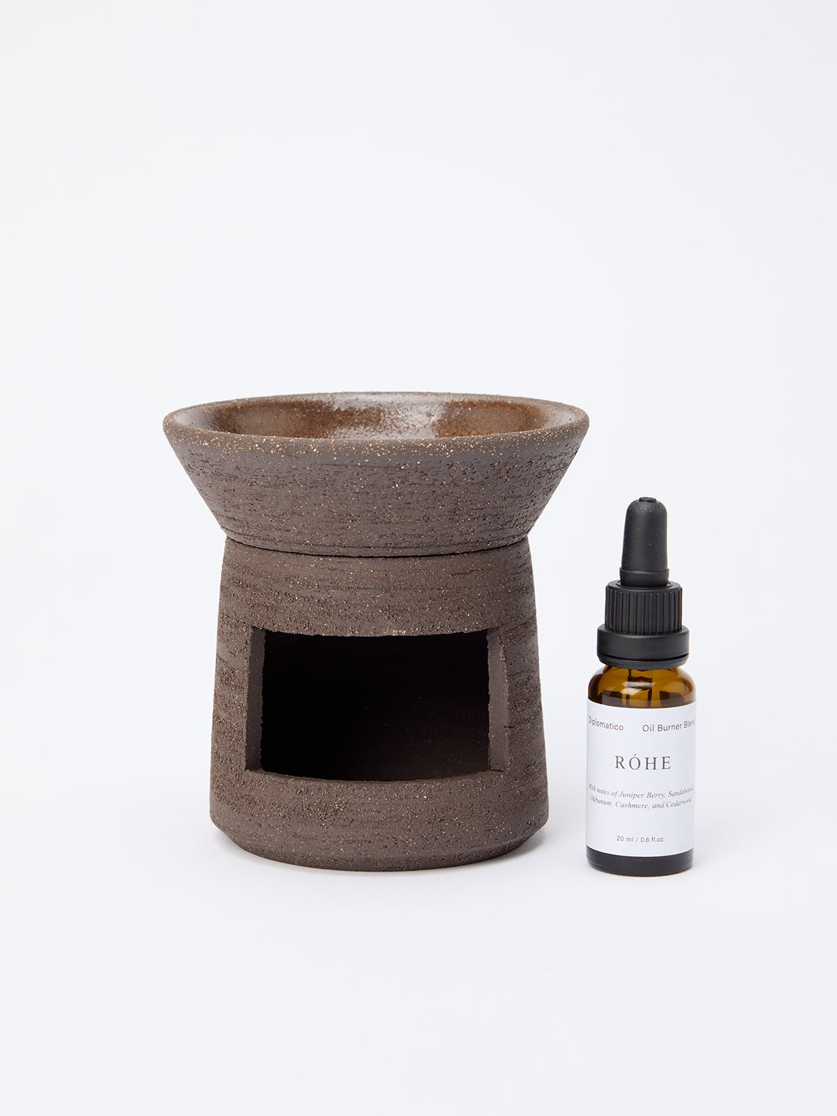 Diplomatico Burner Oil set showcasing a dark-brown ceramic aroma lamp with a RÓHE labeled essential oil blend in an amber glass dropper bottle.